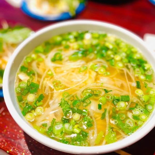 Close-up of a bowl of Pho 9's pho, garnished with green onions and white onions.